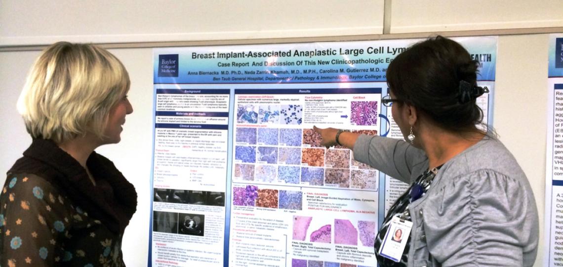 Pathology resident receiving feedback from faculty about her poster presentation.