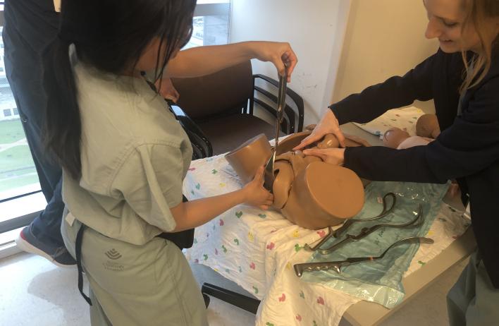A trainee works with a simulation lower torso.
