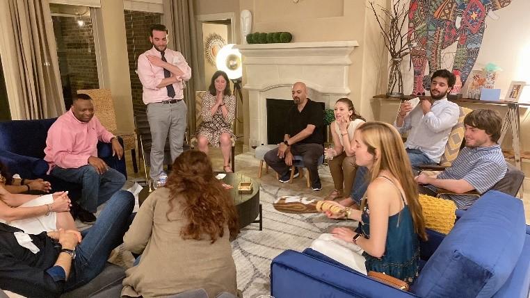 Dr. Dindo’s Birthday Party May 2022. Multiple lab members gather in a living room, sitting in a circle while chatting.