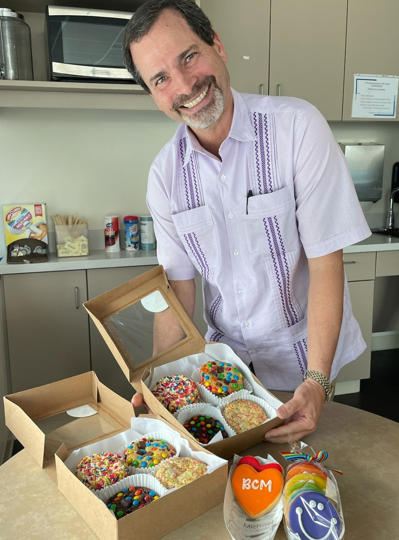To celebrate PRIDE month, faculty and staff pose with sweet treats they plan to eat from Michael's Cookie Jar.
