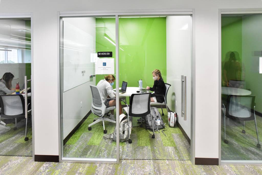 Two students work in a private room with glass doors