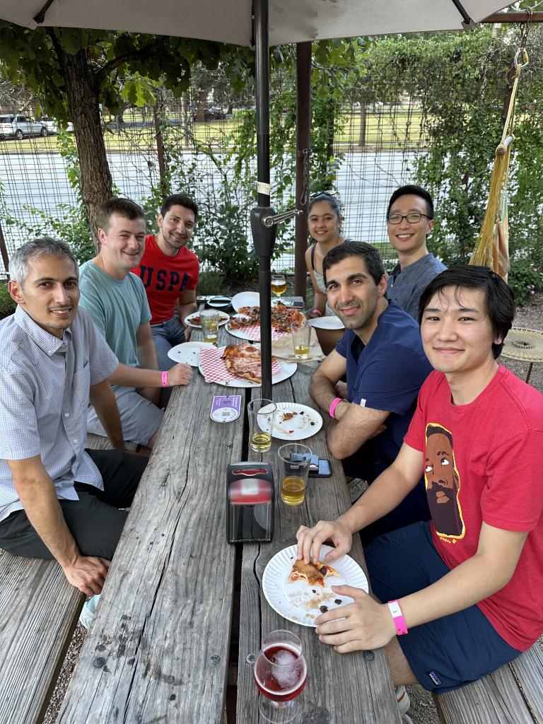 A smiling group eating pizza at a patio restaurant