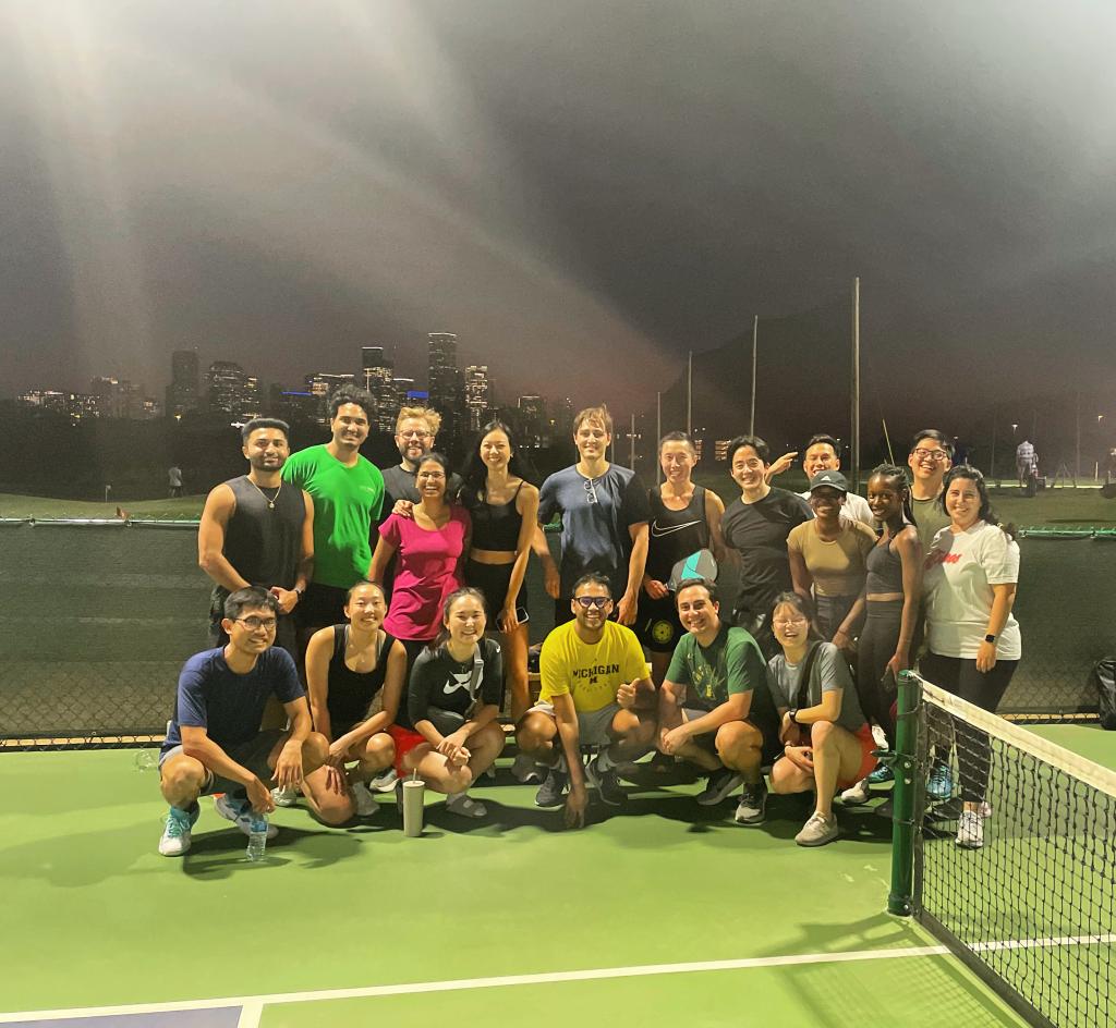 A large group of people post on a tennis court.