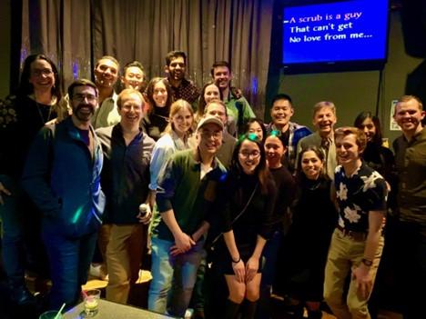 group of people smiling in front of a karaoke stage