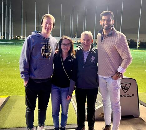 4 people smiling at top golf