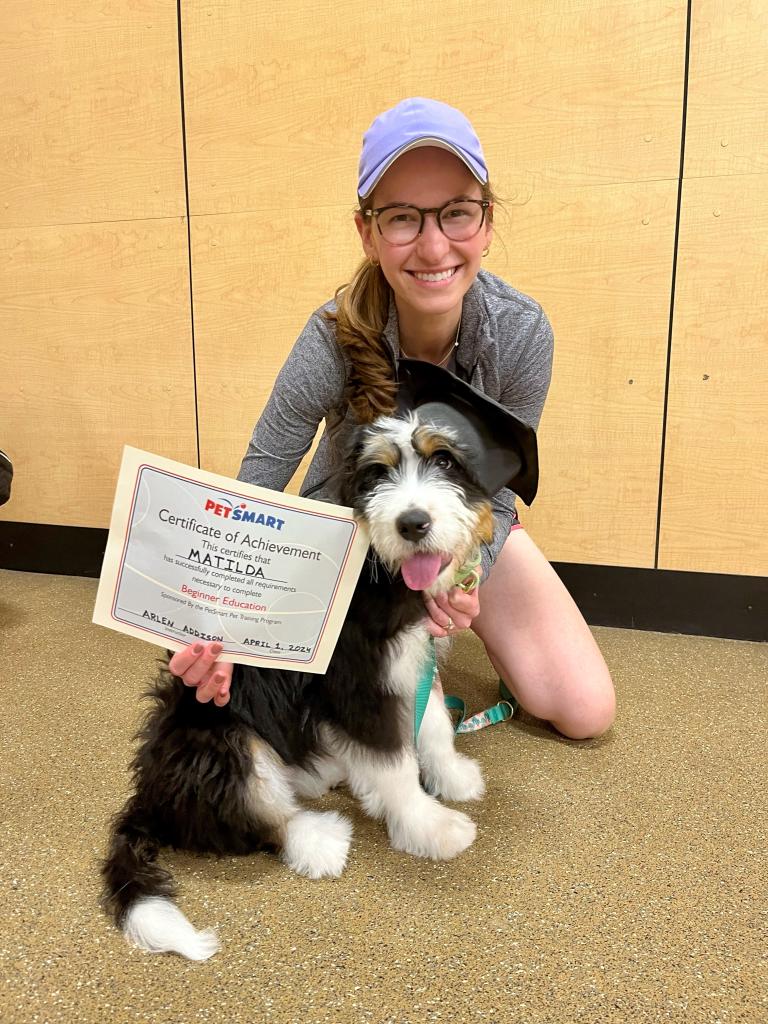 a woman and her dog, holding a certificate of training completion