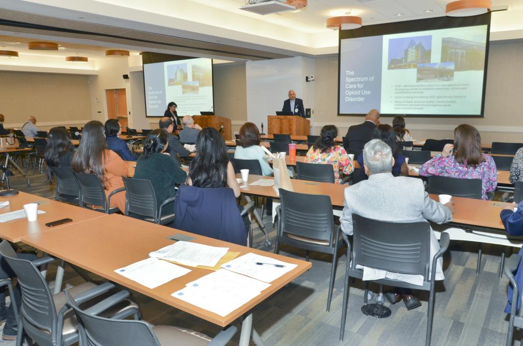 people sitting in a lecture room, looking at a presentation