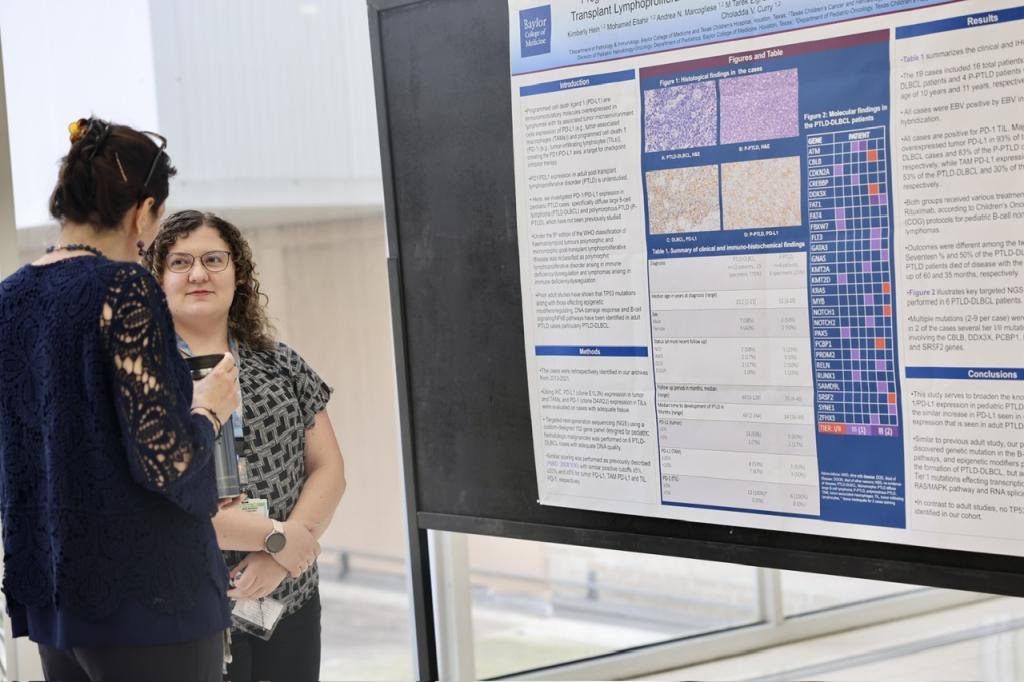 two people talking beside a poster board