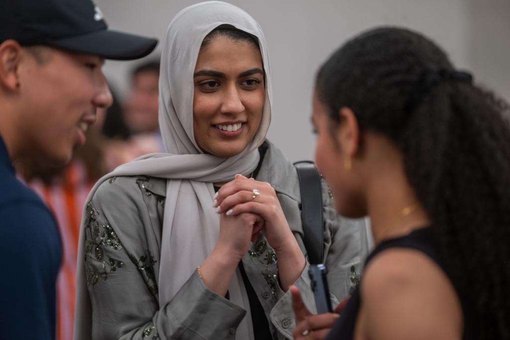 A trio standing close and smiling at each other