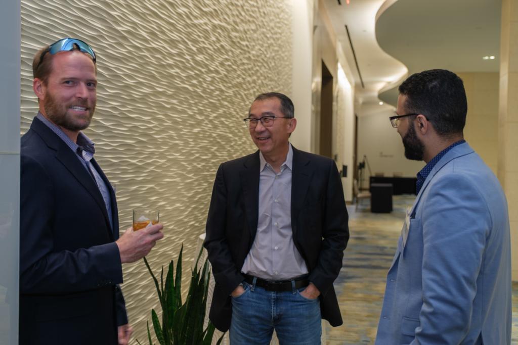 Three people smiling and laughing in a large hallway