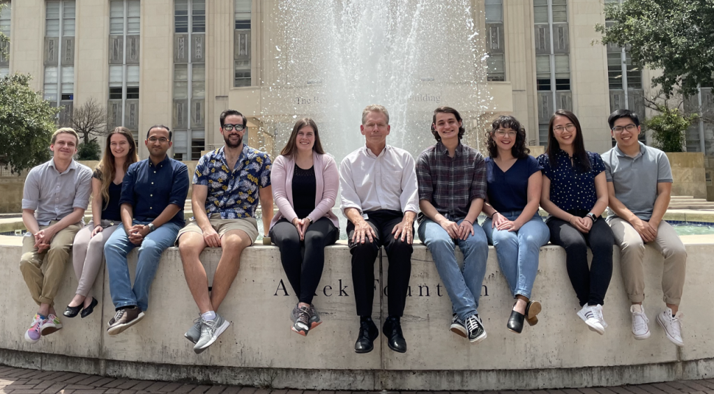 Members of the Cooper Lab sit in front of the fountain