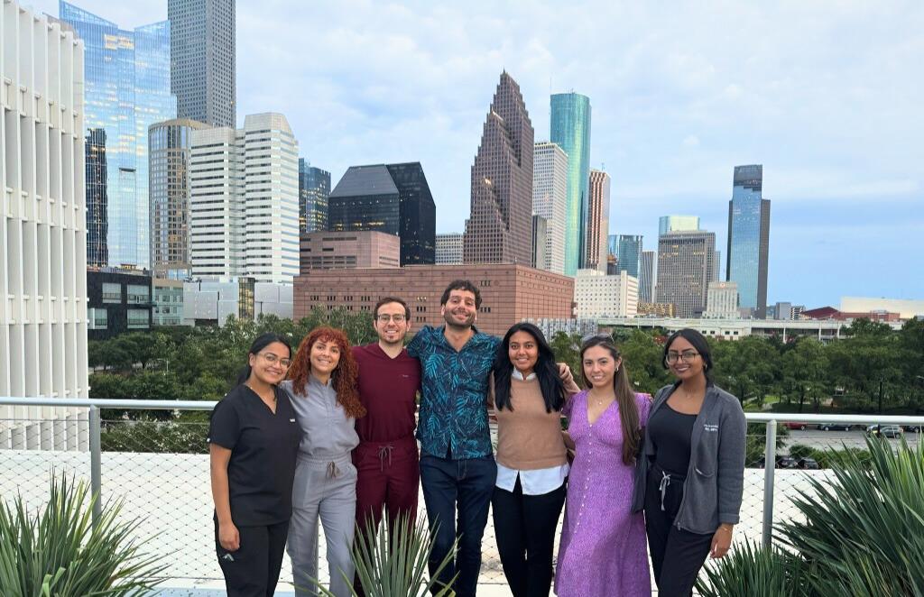 group of people smiling in fron the the houston skyline