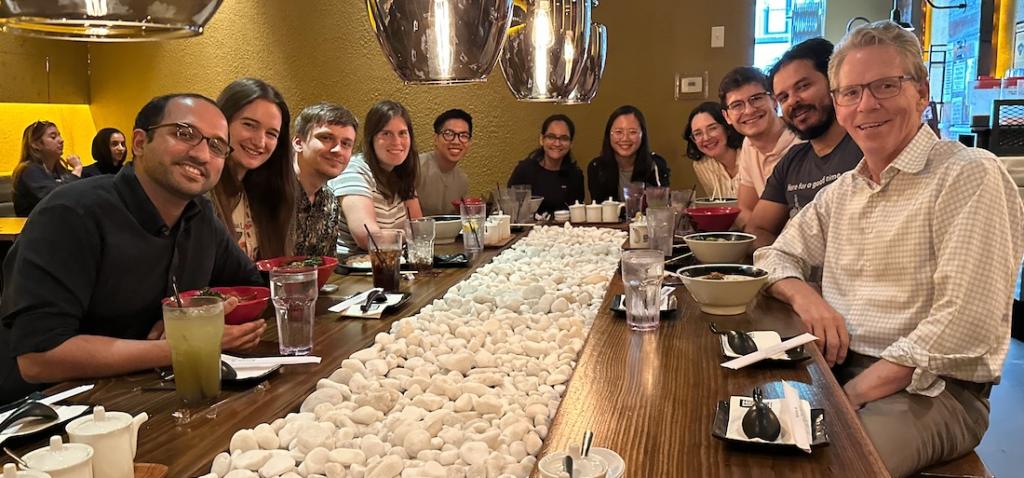 people sitting at a long dinner table smiling