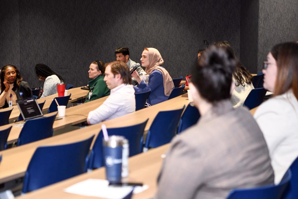 A presentation attendee holds a microphone while asking a question