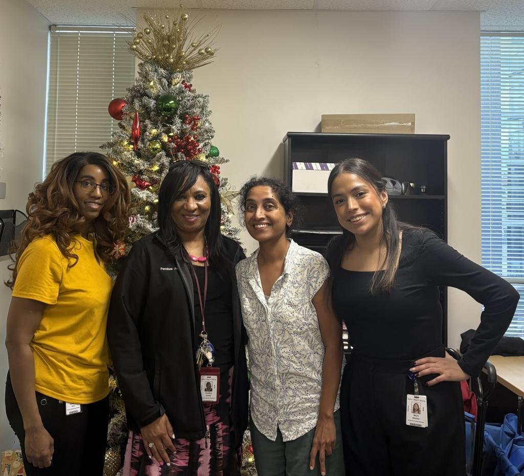 4 people standing in front of a christmas tree, smiling