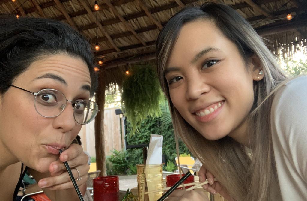Two people smiling while enjoying an off-campus hangout on a porch.