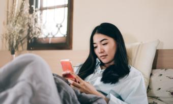 Woman in bed looking at her phone