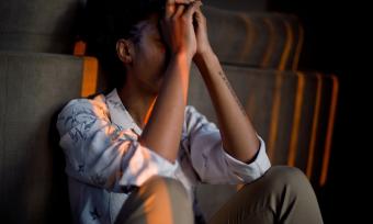 A woman sitting with her hands covering face to represent depression