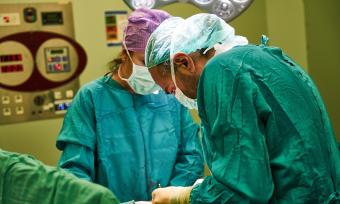 Photo of a surgeon slouching over the patient in the OR.