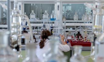 Photo of a woman taken from behind of her working in a lab. 