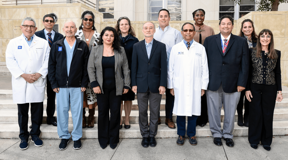 13 Members of the Inclusion and Excellence Council stand shoulder-to-shoulder outside.