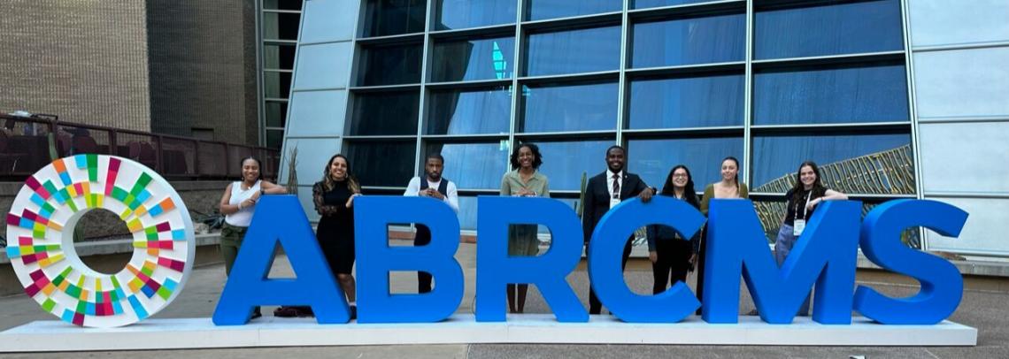 Eight people standing behind giant letters that read ABRCMS