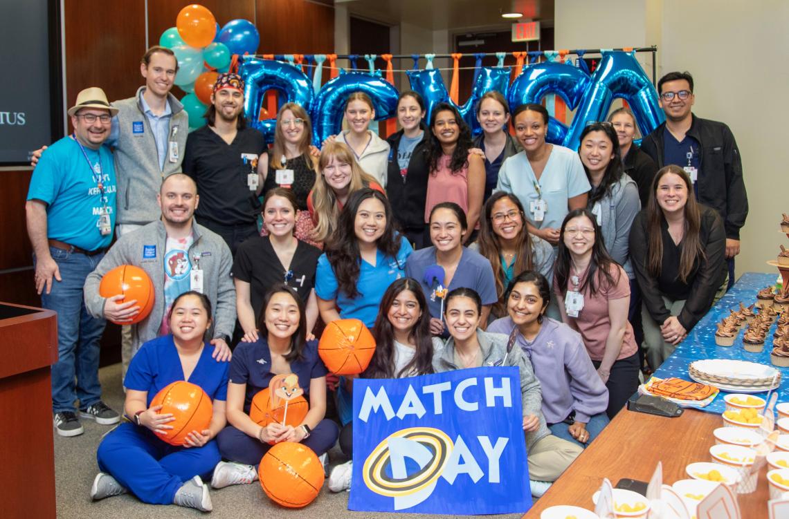 group of people smiling behind a small "match day" sign