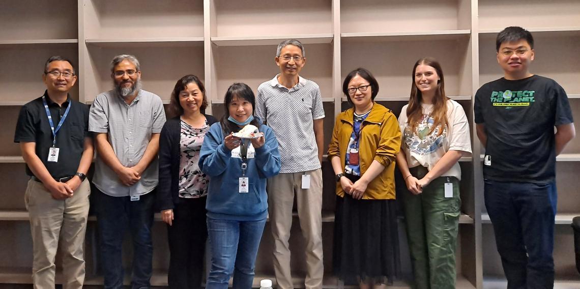 group of people smiling in front of shelves