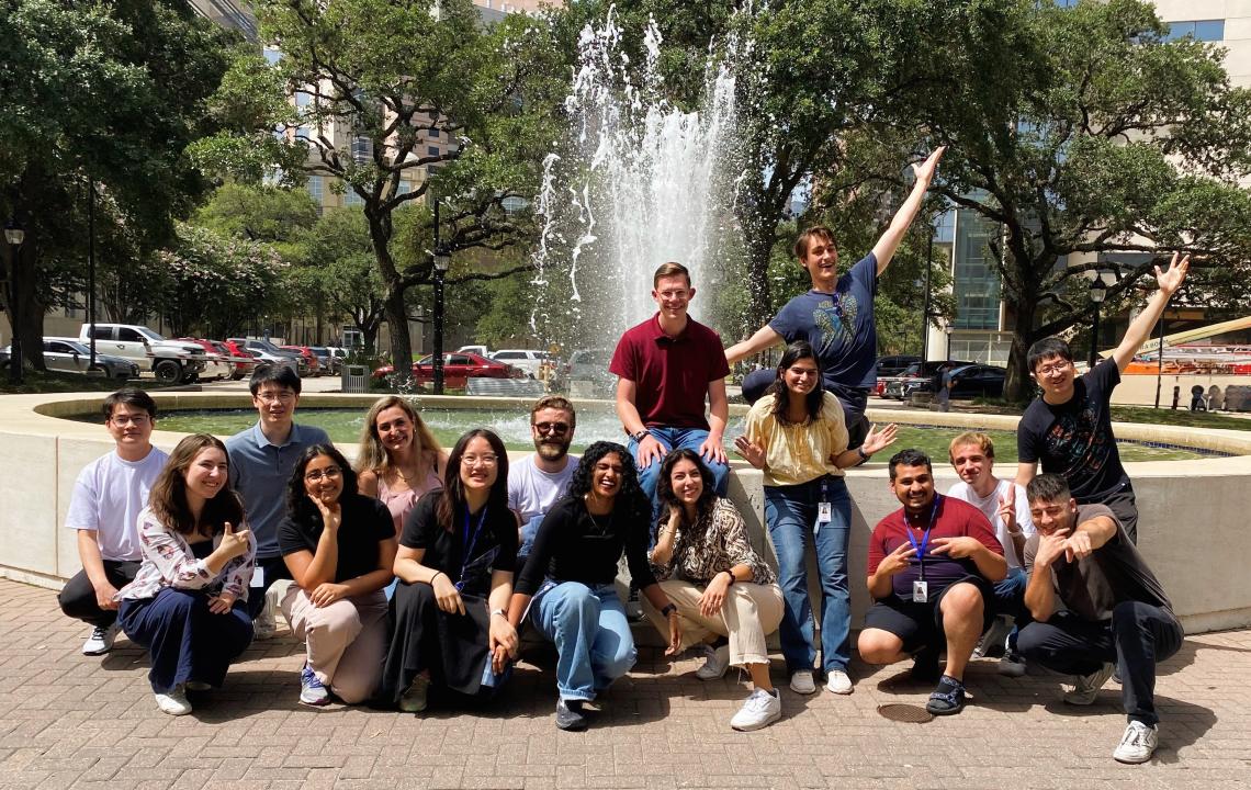 A group of students posing in front of a tall water fountain