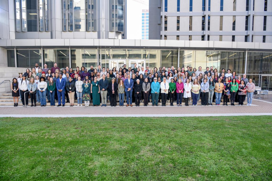 large group of people standing outside together smiling