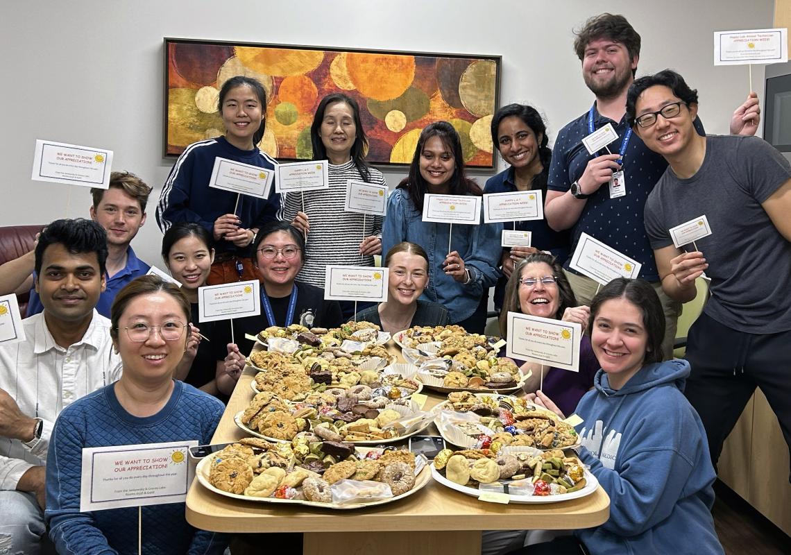 group of people holding signs around a table with cookies