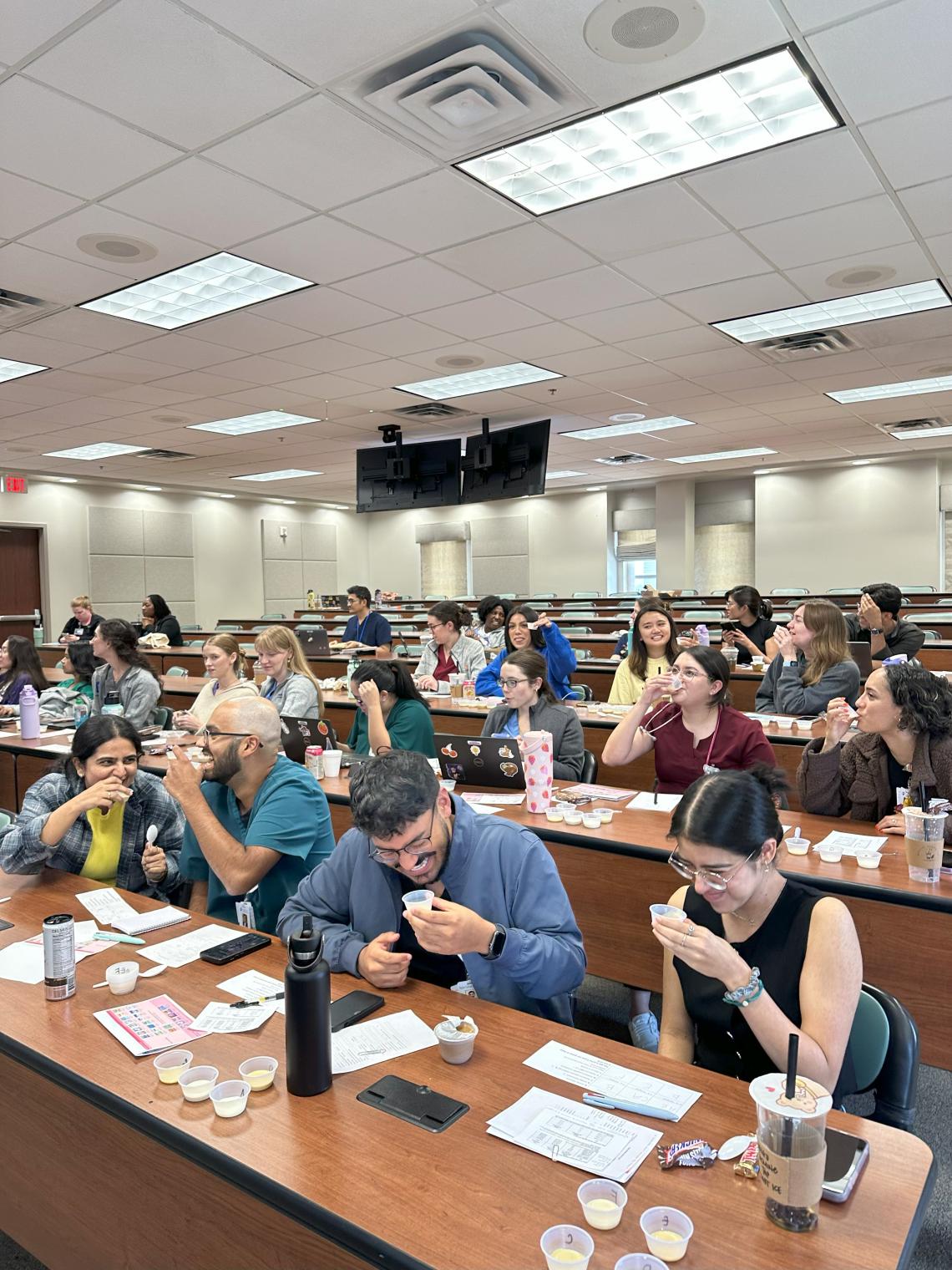 people in a classroom, trying baby formula and giggling