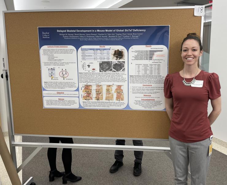 Bridget Stroup standing in front of her poster presentation about Lysinuric Protein Intolerance at the Lawrence Family Bone Disease Program of Texas 2022 Scientific Retreat