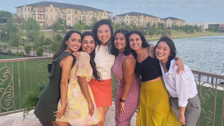 Six residents pose in front of a large pond