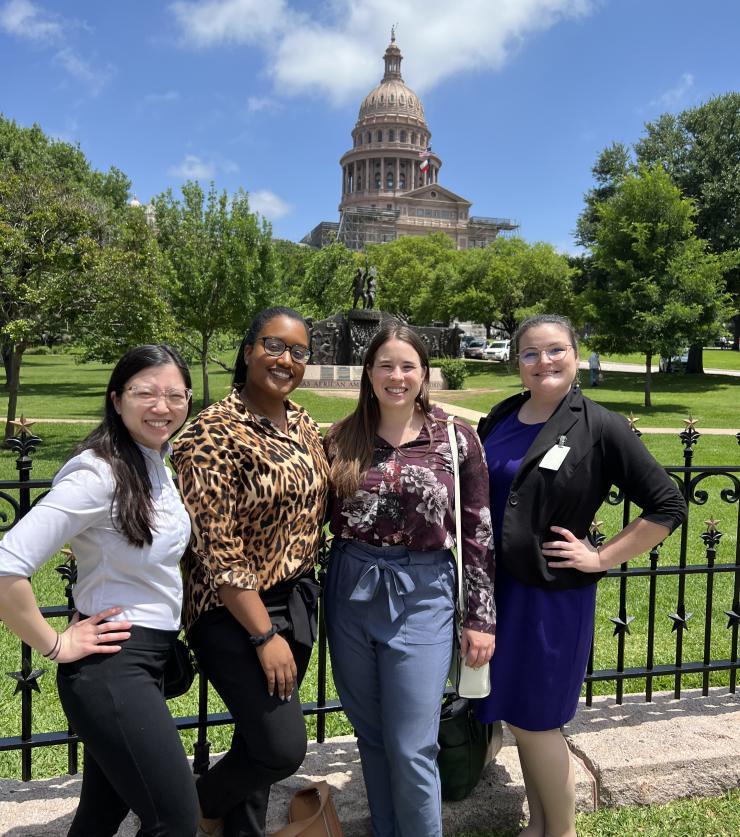 Four residents pose with the capital building in Austin, Texas in the background