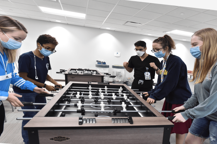 Five students gathered around a foosball table.