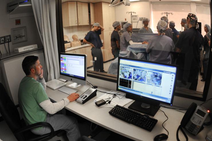 An observer watching a group inside the anesthesiology simulation lab 