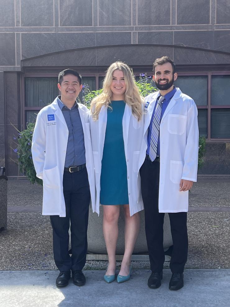 3 people in white doctor coats smiling outside