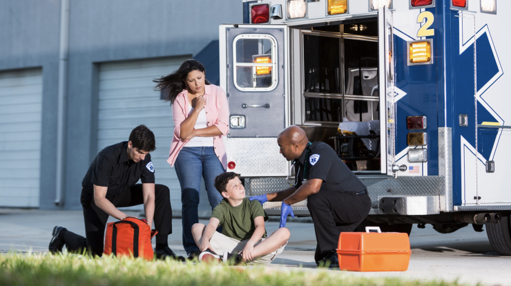 child being seen by two EMTs with his mom looking in on him