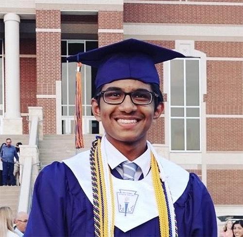 man smiling outside wearing graduation gown