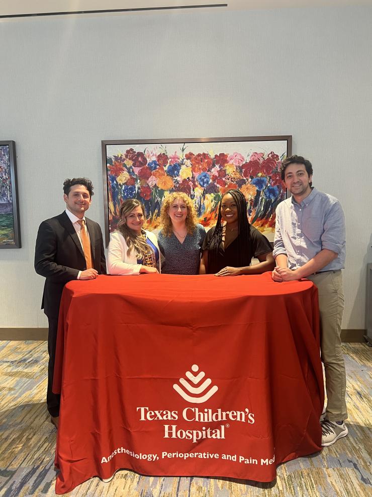 5 people standing behind a Texas Children's Hospital -branded table smiling
