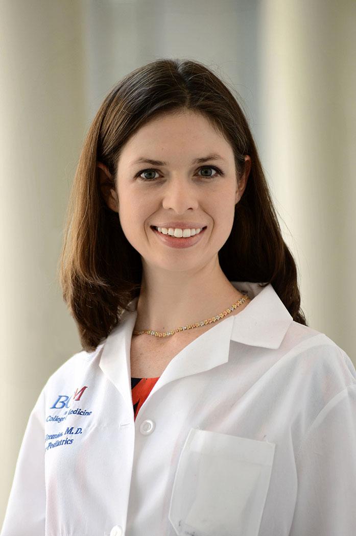 woman with shoulder length brown hair in a whote doctor coat smiling