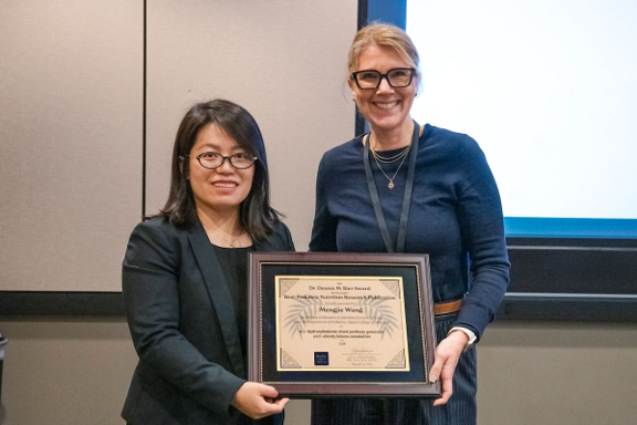 Two women holding a framed certificate