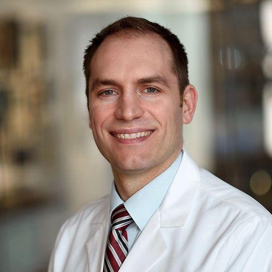 man with a buzzcut in a doctor coat smiling