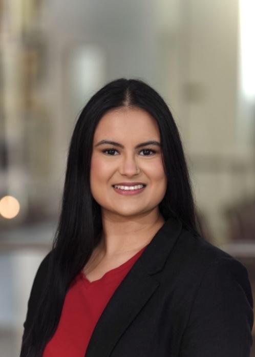 woman with long black hair in a red top and black blazer smiling