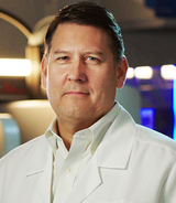 man in a white suit and short smiling lightly