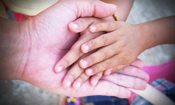 Adult hands holding child's hands