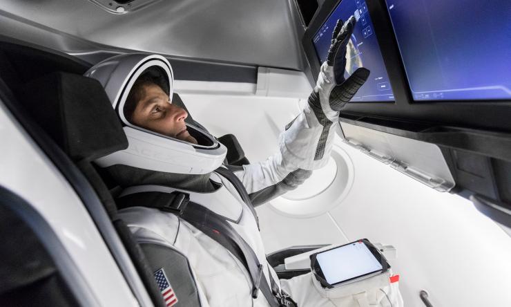 NASA Astronaut Suni Williams, fully suited in SpaceX’s spacesuit, interfaces with the display inside a mock-up of the Crew Dragon spacecraft in Hawthorne, California, during a testing exercise on Tuesday, April 3, 2018.
