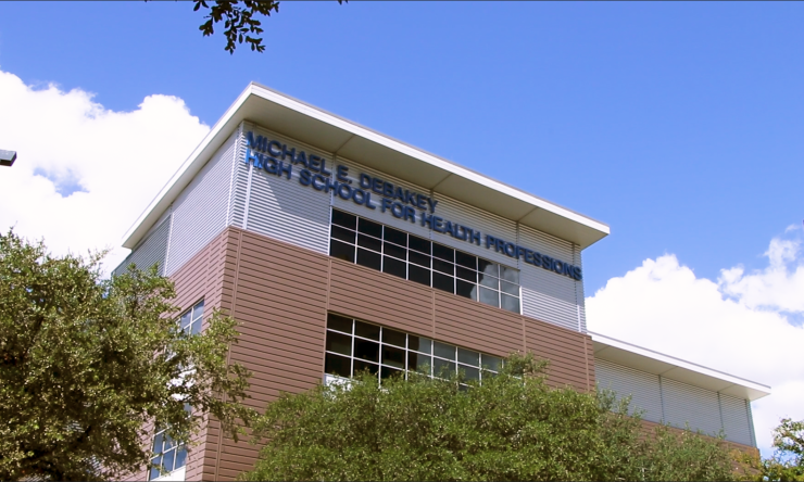 Photograph of the exterior of the DeBakey High School for Health Professions with a blue sky and clouds in the background and trees in the foreground.