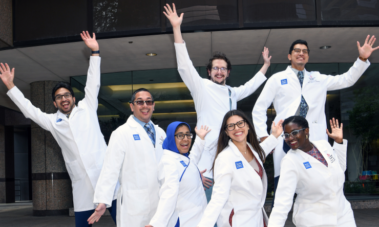 Members of the Pediatric Critical Care Medicine Fellowship pose in a silly fashion, arms waving and looking like they're dancing.